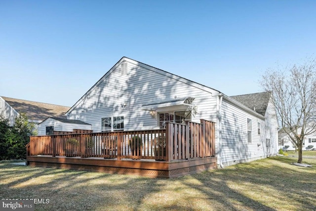 rear view of house featuring a wooden deck and a yard