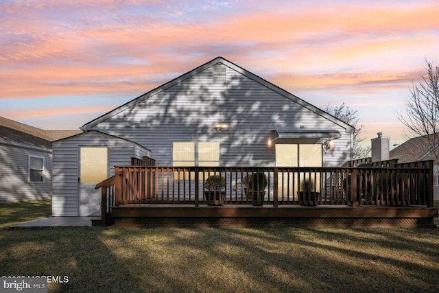 back of house at dusk featuring a deck and a yard