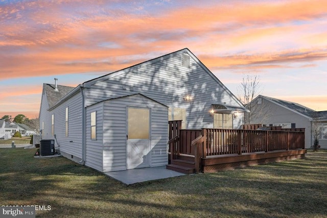 back of house featuring a wooden deck, central air condition unit, and a lawn
