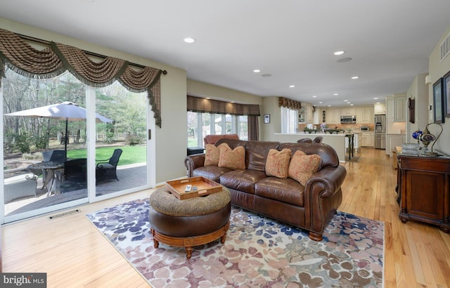 living area with light wood-type flooring, visible vents, and recessed lighting