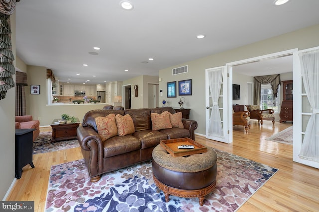 living area featuring baseboards, light wood-style flooring, visible vents, and recessed lighting