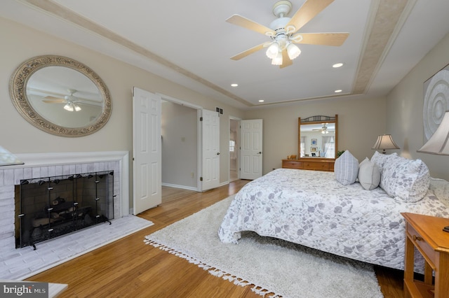 bedroom with baseboards, recessed lighting, wood finished floors, and a fireplace