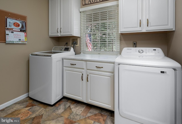 clothes washing area featuring cabinet space, stone finish flooring, baseboards, and separate washer and dryer