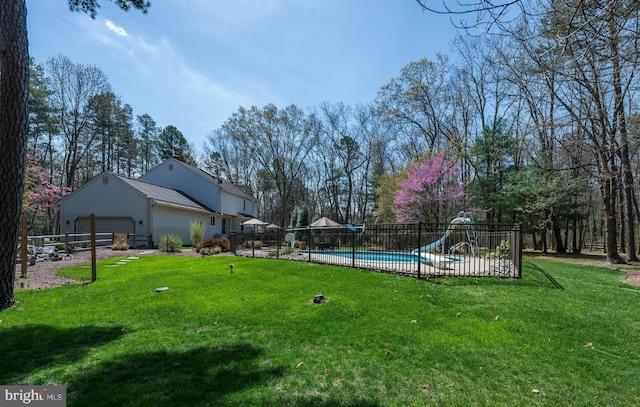 view of yard with fence, a fenced in pool, and a garage