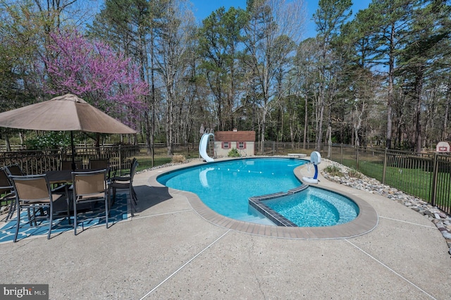 view of pool with a water slide, fence, a patio, and a pool with connected hot tub