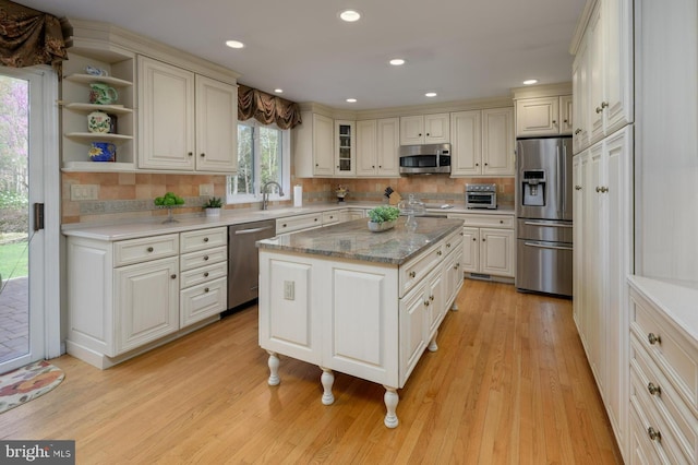 kitchen featuring stainless steel appliances, decorative backsplash, light wood-style floors, and a kitchen island