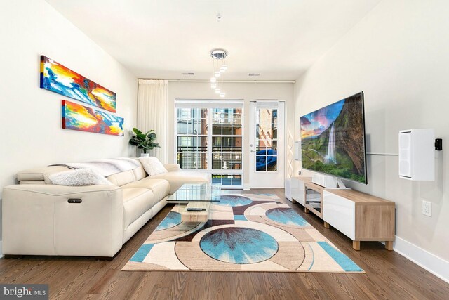 living area featuring baseboards, visible vents, and wood finished floors