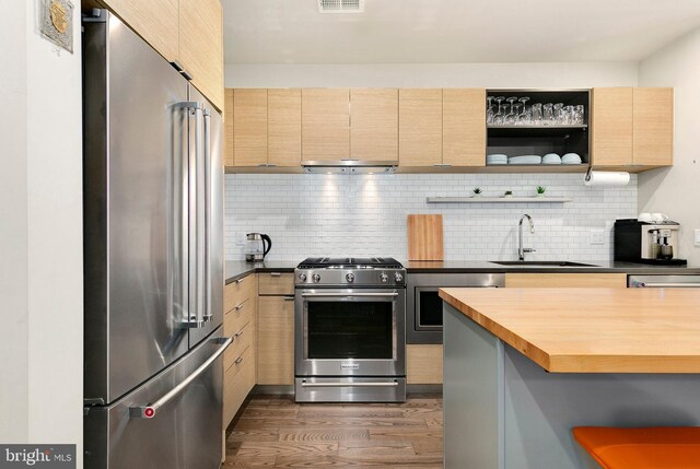 kitchen featuring a sink, dark wood-style flooring, light brown cabinets, and stainless steel appliances