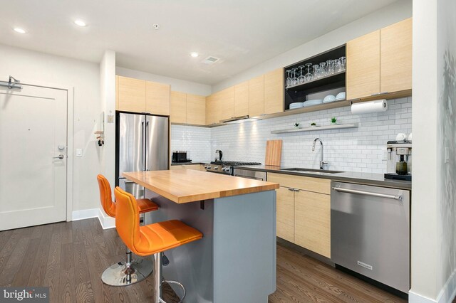 kitchen featuring a sink, appliances with stainless steel finishes, light brown cabinetry, and wood counters