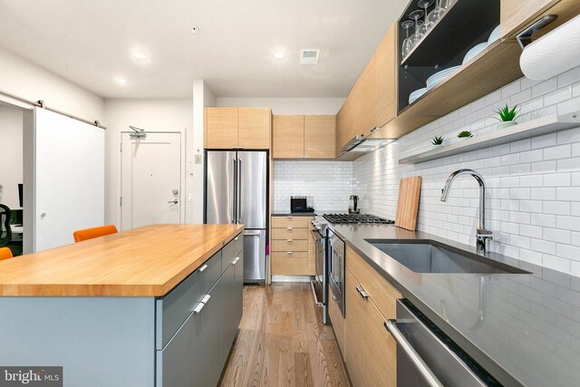 kitchen featuring visible vents, open shelves, butcher block counters, a sink, and stainless steel appliances