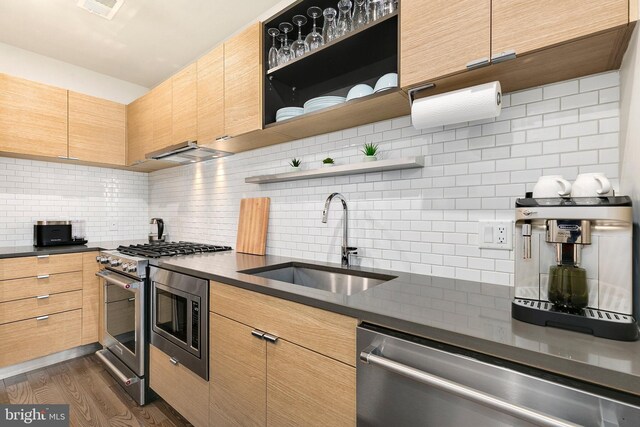 kitchen featuring a sink, backsplash, dark countertops, and stainless steel appliances