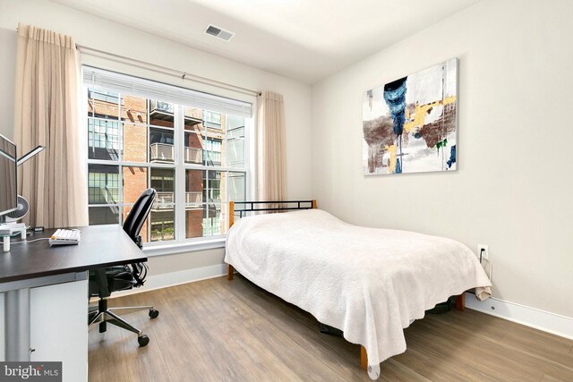 bedroom featuring baseboards, visible vents, and wood finished floors