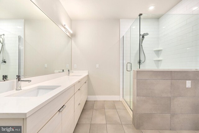 bathroom featuring a sink, baseboards, tile patterned flooring, and a shower stall