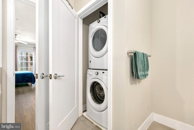 washroom featuring laundry area, stacked washer and dryer, and baseboards
