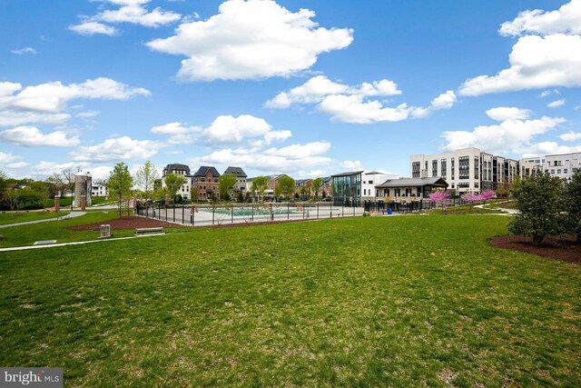 view of community featuring a swimming pool, fence, and a yard