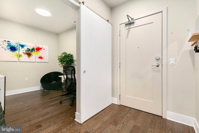 foyer entrance with baseboards, a barn door, and wood finished floors