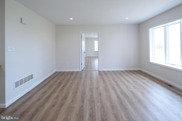 unfurnished room featuring wood finished floors, recessed lighting, baseboards, and visible vents