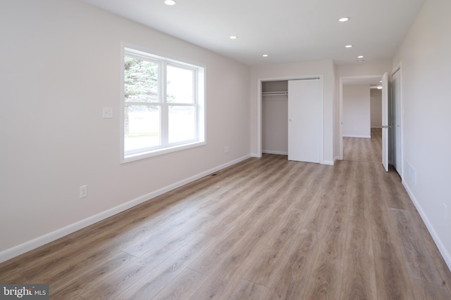 unfurnished bedroom with light wood-type flooring, a closet, baseboards, and recessed lighting