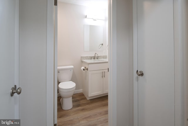 half bath featuring toilet, vanity, and wood finished floors
