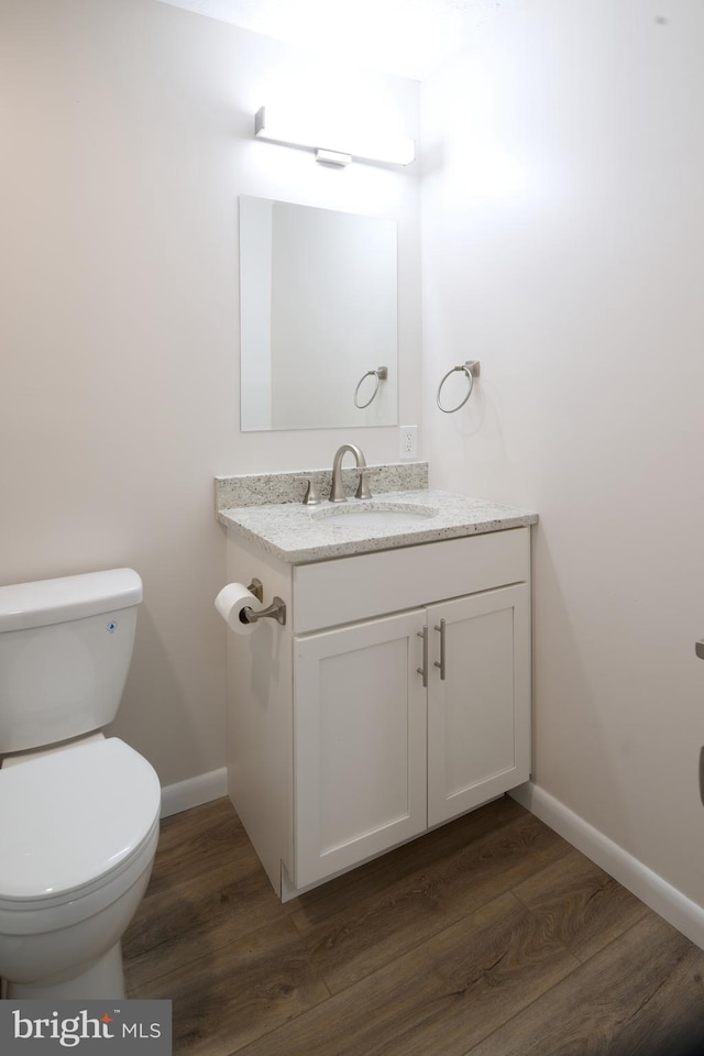 bathroom featuring toilet, wood finished floors, baseboards, and vanity