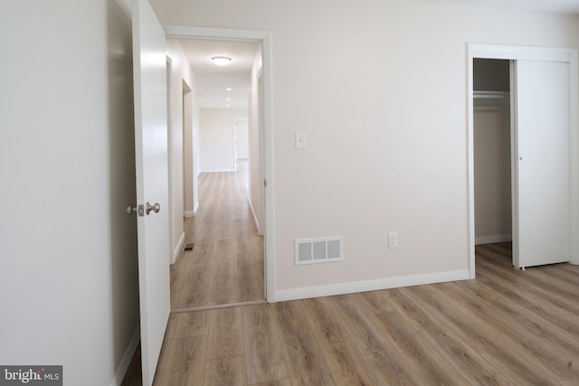 unfurnished bedroom with wood finished floors, a closet, baseboards, and visible vents