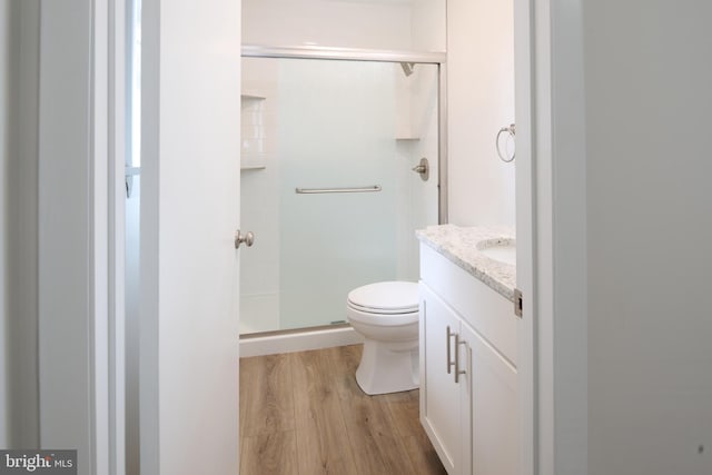 full bathroom featuring vanity, toilet, a shower stall, and wood finished floors