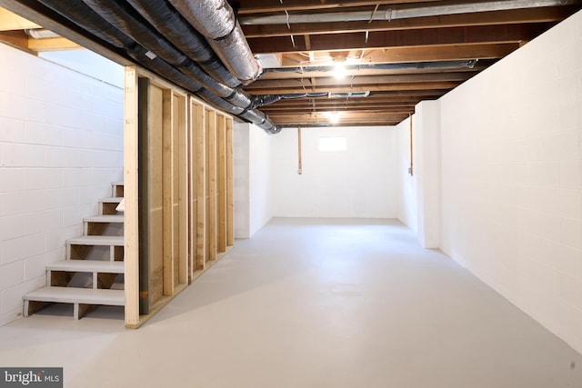 unfinished below grade area featuring concrete block wall and stairway