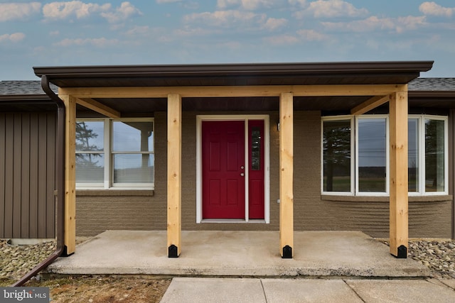 property entrance with board and batten siding and roof with shingles