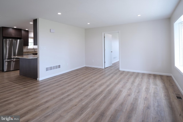 unfurnished living room with light wood finished floors, baseboards, and visible vents