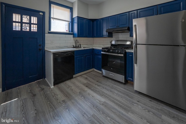 2105 S Woodstock St, Philadelphia, PA 19145 - kitchen with light countertops, blue cabinetry, under cabinet range hood, stainless steel appliances, and a sink