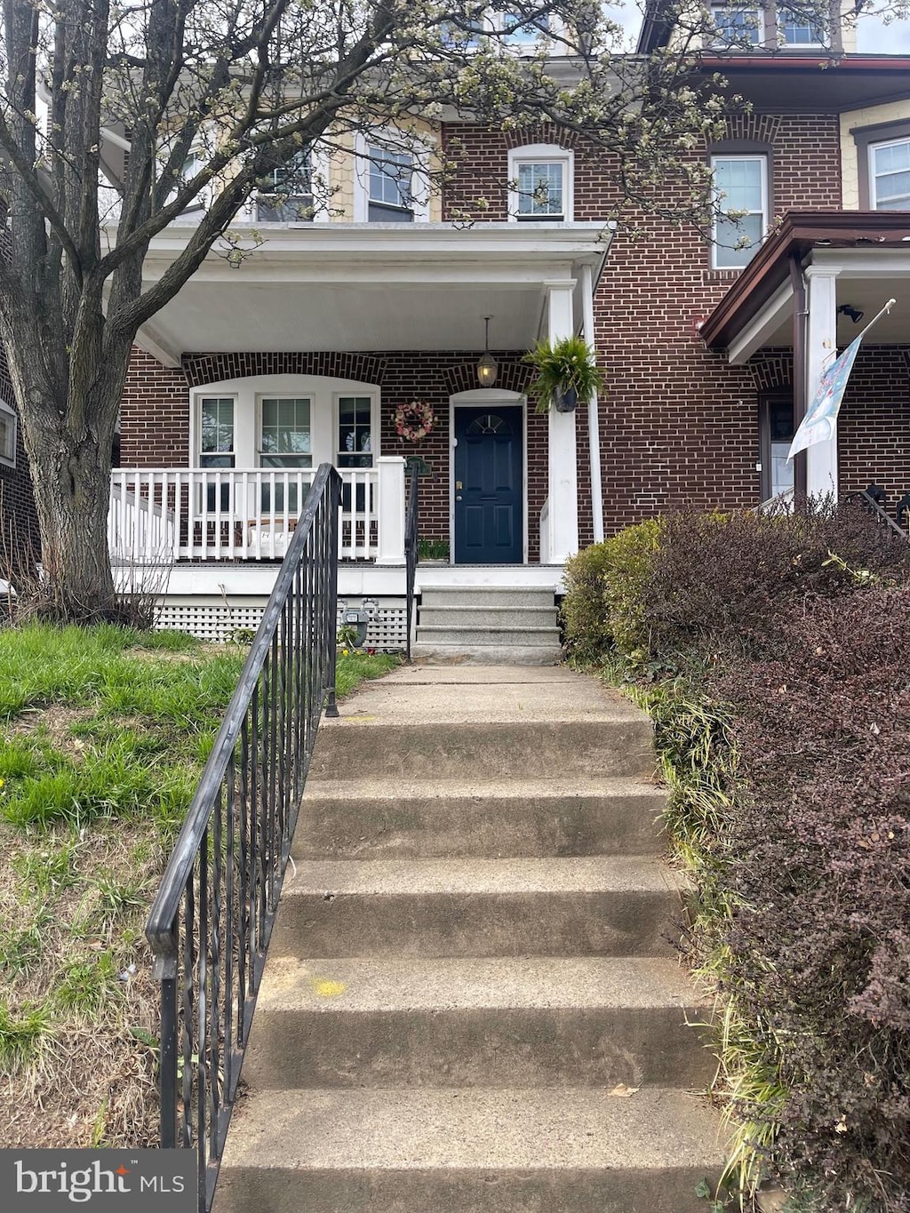 property entrance with covered porch and brick siding