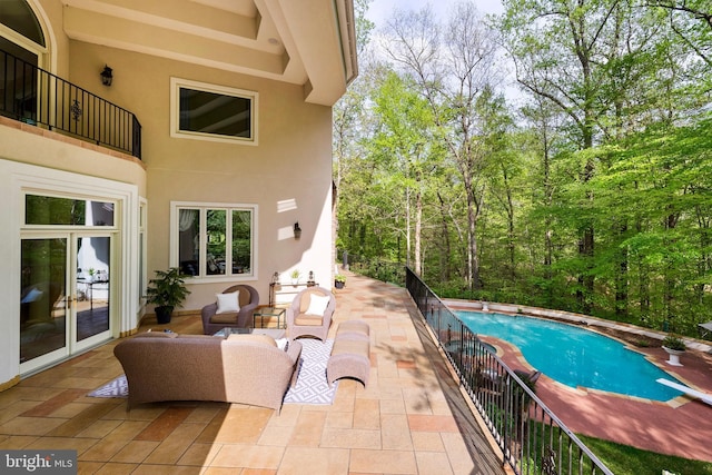 outdoor pool with a diving board, an outdoor hangout area, and a patio area