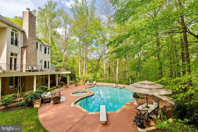 outdoor pool with a diving board, an in ground hot tub, and a patio area