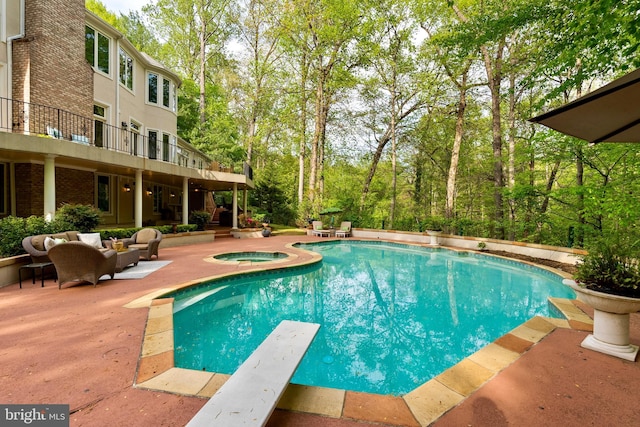pool featuring a patio, a diving board, an in ground hot tub, and an outdoor hangout area