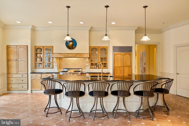 kitchen featuring dark countertops, a sink, paneled refrigerator, ornamental molding, and glass insert cabinets