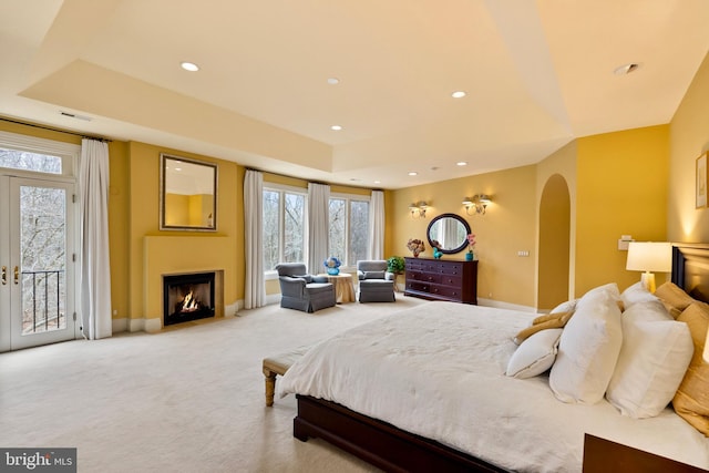 bedroom with arched walkways, access to outside, light carpet, and multiple windows
