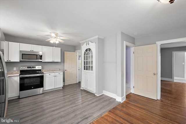kitchen with dark wood-style floors, stainless steel appliances, ceiling fan, white cabinetry, and baseboards