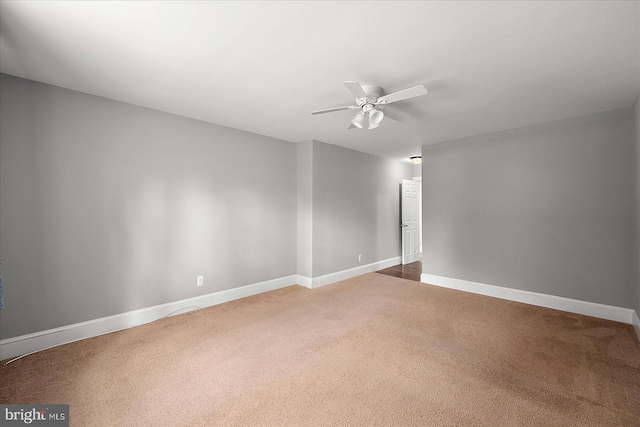 carpeted spare room featuring ceiling fan and baseboards
