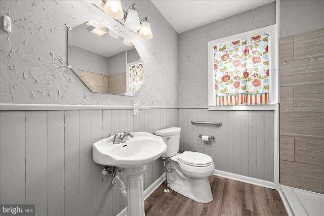 full bathroom with a shower, wood finished floors, toilet, and wainscoting