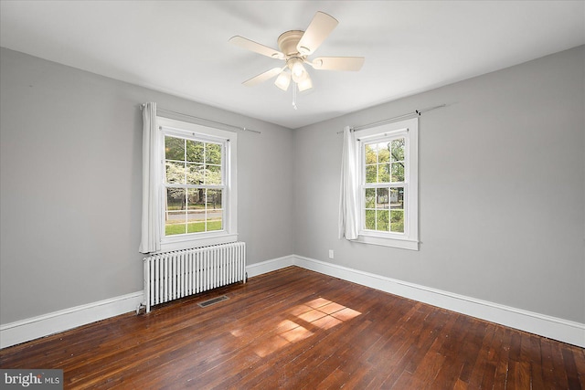 spare room with visible vents, ceiling fan, baseboards, wood-type flooring, and radiator