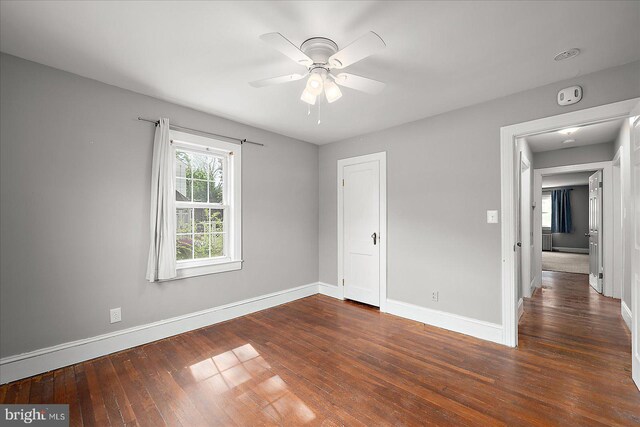 unfurnished bedroom featuring ceiling fan, hardwood / wood-style flooring, and baseboards
