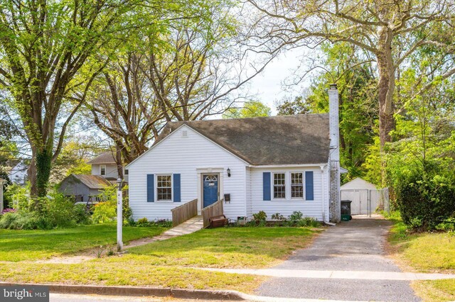view of front of home featuring fence, roof with shingles, a chimney, and a front lawn
