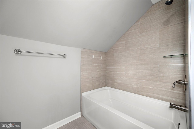 full bathroom featuring a bathtub, a shower, lofted ceiling, and baseboards
