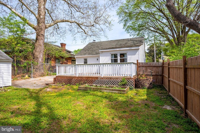 rear view of house featuring a yard, a wooden deck, and a fenced backyard