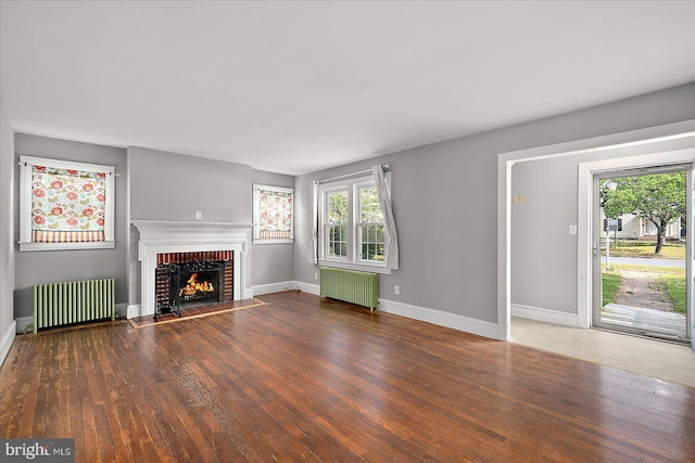 unfurnished living room with radiator, hardwood / wood-style floors, baseboards, and a fireplace