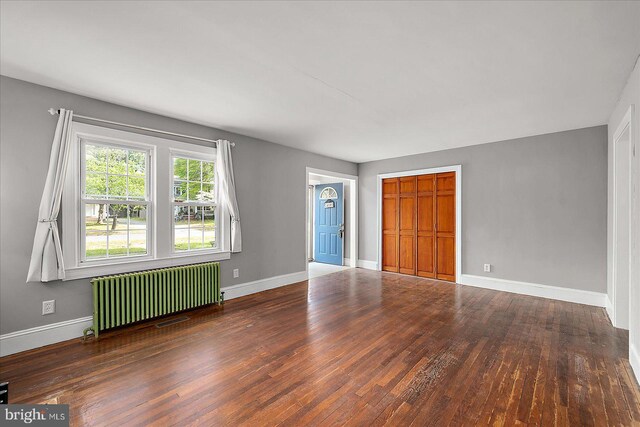 interior space with radiator heating unit, hardwood / wood-style flooring, and baseboards