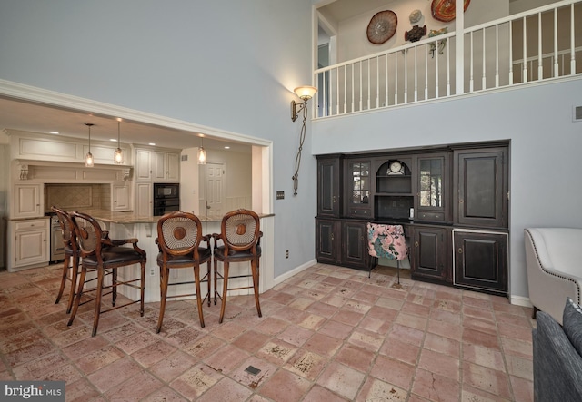 dining room featuring stone tile floors, a high ceiling, visible vents, and baseboards