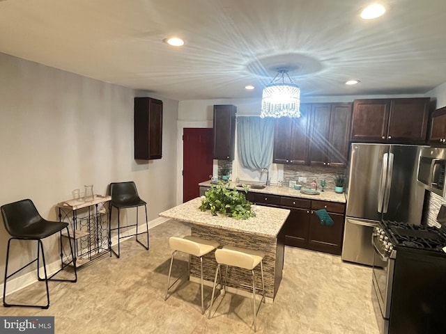 kitchen featuring tasteful backsplash, a kitchen breakfast bar, recessed lighting, dark brown cabinets, and appliances with stainless steel finishes