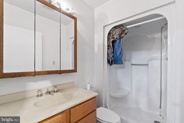 bathroom featuring a shower stall, toilet, and vanity