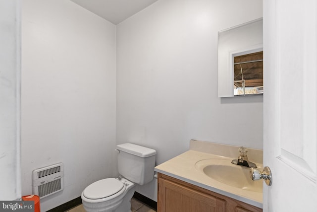 bathroom featuring heating unit, toilet, and vanity